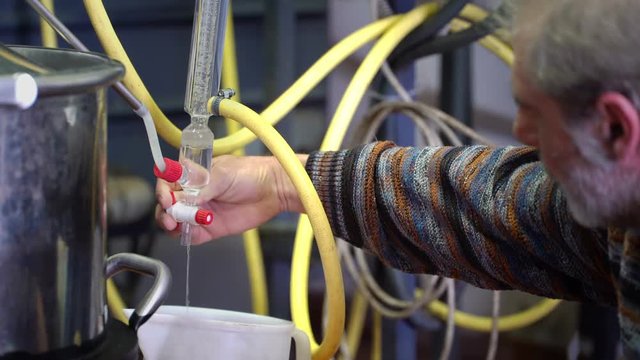 Production of perfume essences using steam in a distillation cube in a small alpine village. An elderly man evaporates parfimer essentia from wild herbs. Real people.