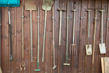 Diverse Arbeitsgeräte für die Gartenarbeit aufgehängt an einem Holzschuppen
