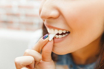 close up on a beautiful girl while enjoying a chewing gum after lunch - obrazy, fototapety, plakaty