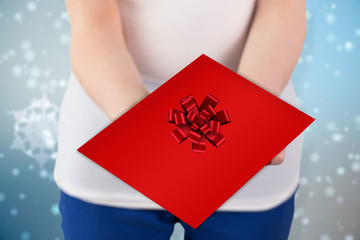 Woman holding red and white gift against red christmas ribbon