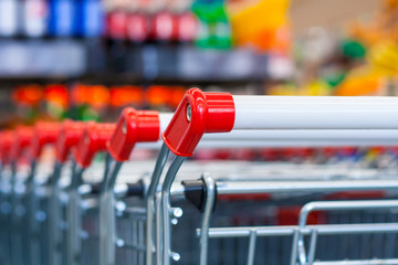 Close up view of a row of push carts in a supermarket on the background of counters in blur
