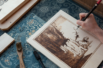 Artisan at work with his wood burning tool. The Pyrography is an engraving technique by means of a heat source, on wood, leather, cork and other materials