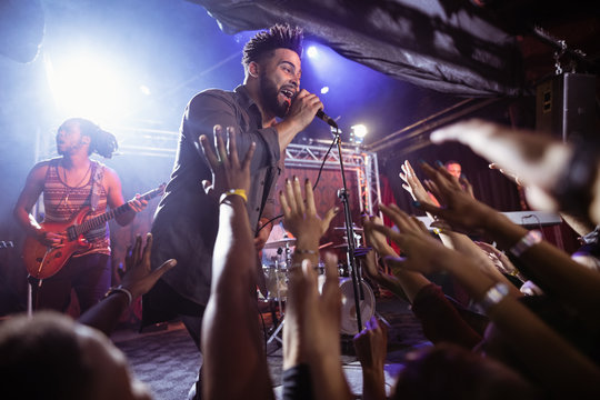 Male singer performing on stage by crowd at nightclub