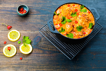 Creamy South Indian style Roast Chocken Curry on black pot on dark blue wooden rustic table