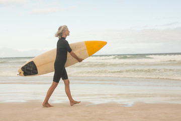 Fototapeta na wymiar Side view of woman walking with surfboard on shore