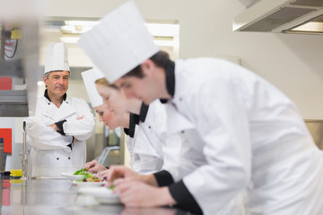 Chef overlooking others preparing salads