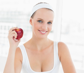 Smiling pretty sportswoman holding an apple