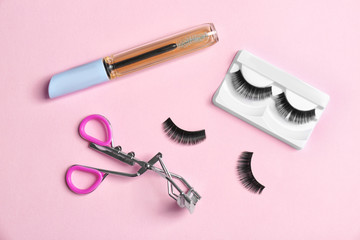 Flat lay composition with false eyelashes, oil and curler on color background