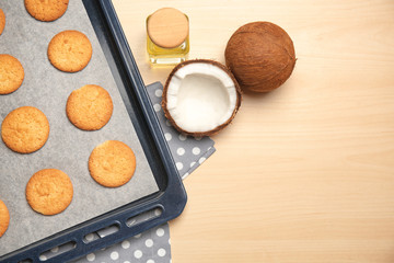 Baking tray with cookies and coconuts on wooden background