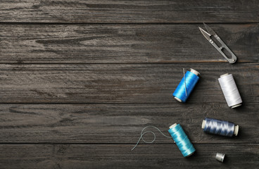 Flat lay composition with sewing threads on wooden background