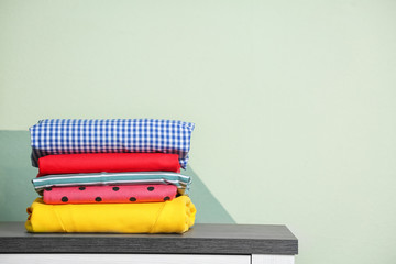 Stack of clean clothes on table against light background © New Africa