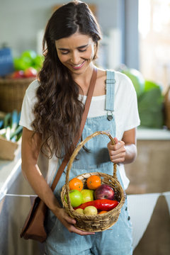 Smiling woman holding a basket of fruits 