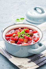 Mushroom borscht, traditional beetroot soup in pot on light blue,concrete background. Selective focus, space for text.