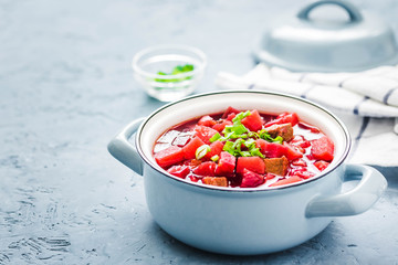 Roasted vegetable borscht, traditional beetroot soup in pot on light blue,concrete background. Selective focus, space for text.