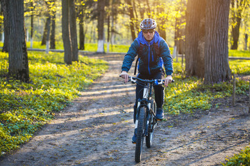 Happy man cyclist rides on a picturesque forest road on a mountain bike.