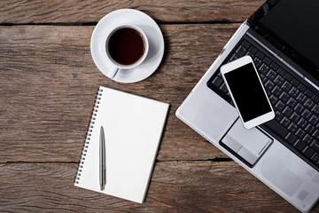 wooden table office stuff with notepad, laptop and coffee cup, notepad, pen, smartphone top view shot