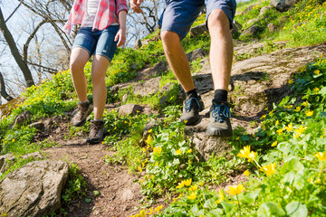 Young Couple Hiking with Backpacks on the Beautiful Rocky Trail at Sunny Evening. Family Travel and Adventure.