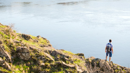 Young Man Traveler with Backpack Enjoing Landscape on Beautiful Rock at Sunny Evening. Travel and Adventure Concept.