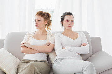 Unhappy friends not talking after argument on couch