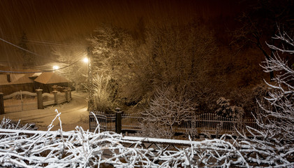 Snow is falling on deserted streets, winter night in village 