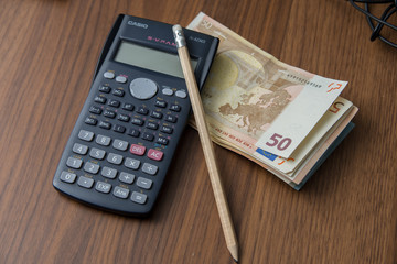 A black calculator and a pencil with euro money.