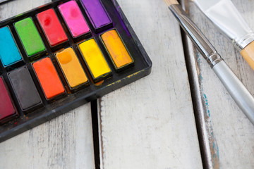 Colorful palette and paintbrushes on wooden surface