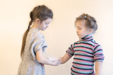 The girl bending her sister's hand. Two, girls, play, doctor. Bandage your arm with a bandage. Hand injury. First aid