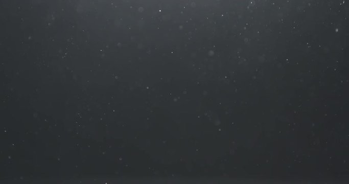Slow motion real dust floating in air over dark background