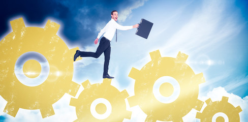 Happy businessman leaping with his briefcase against blue sky