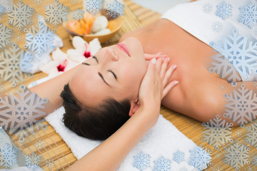 Smiling brunette enjoying a head massage against snowflake frame