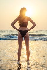 Fototapeta na wymiar beautiful and young woman looks at the sunset beach
