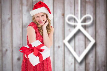 Cute woman in red dress offering gift against blurred christmas decorations on wood