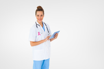 Pretty nurse using tablet pc against white background with vignette