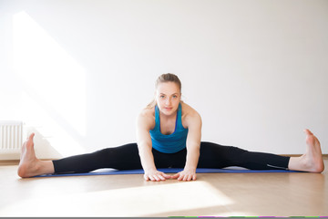 Beautiful athletic blonde girl doing sports exercises on a sports mat.