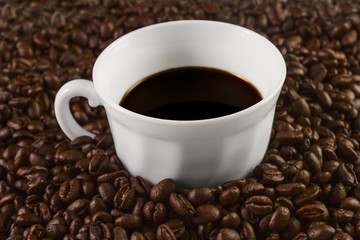 Cup filled with coffee on coffee beans background. Selective focus.