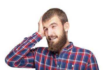 A young bearded man in a plaid shirt is experiencing an annoying mistake or oversight. Emotional portrait on a white background.