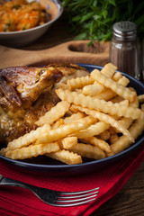 Roasted chicken with french fries on a plate.