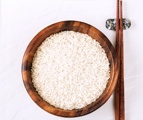 Isolated handful of raw rice in the wood bowl on white background