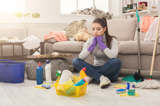 Upset woman cleaning house with lots of tools