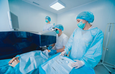 Laser vision correction. A patient and team of surgeons in the operating room during ophthalmic...