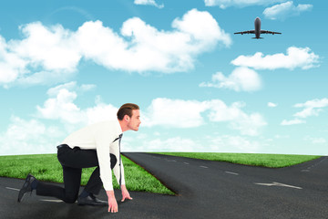 Businessman with hands and one knee on the floor against road leading out to the horizon