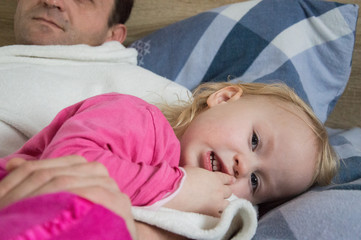 little girl lies on bed with her father, morning on a day off