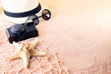 Starfish with sunglasses, camera and hat on beach sand