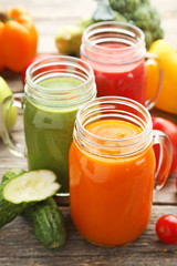 Vegetables smoothie in jars on wooden table