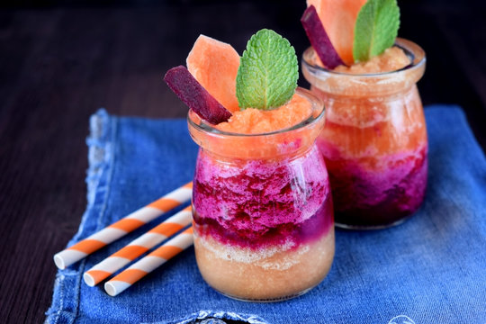 Layered smoothie with beet, carrot and apple in glass jars