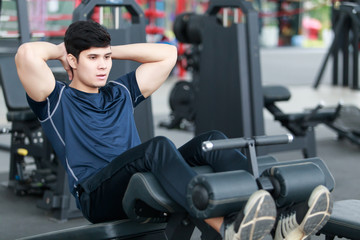 Fototapeta na wymiar Athletic young man exercising equipment at gym, workout in fitness center.
