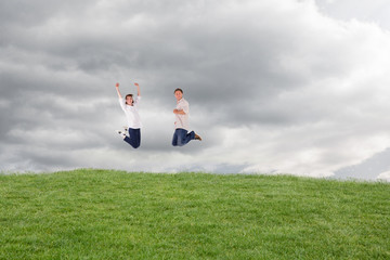 Couple jumping in the air against cloudy sky