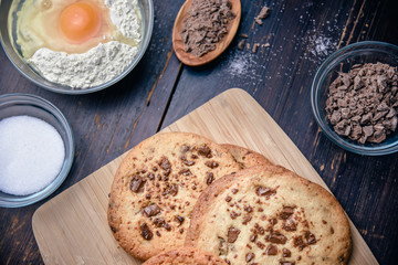 Chocolate cookies on wooden table with flour eggs and ingredients