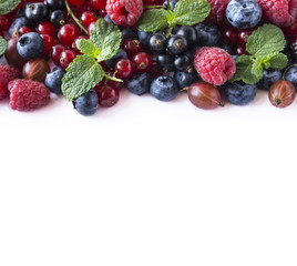 Mix berries on a white background. Berries and fruits with copy space for text. Black-blue and red food. Ripe blueberries, raspberries, gooseberries, red and black currants on white background. 