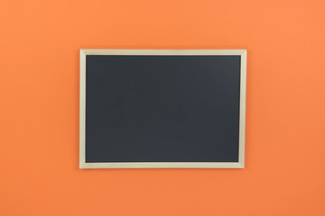 Empty chalkboard on orange background with copy space.